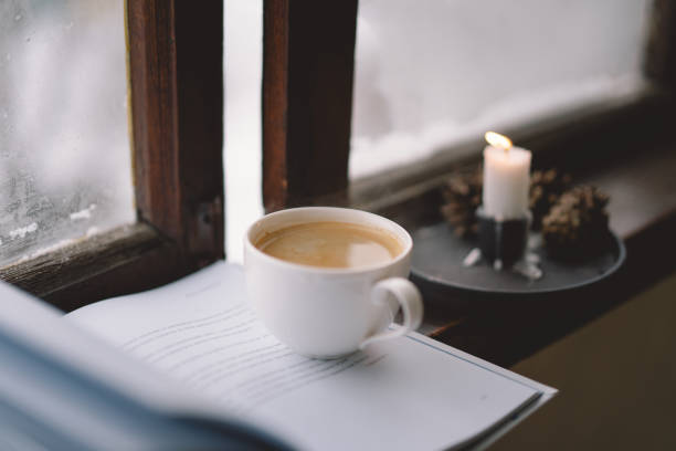 A warm mug resting beside an open journal on a sunlit windowsill